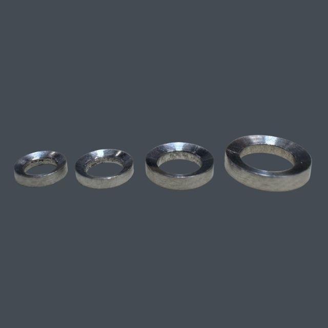 Four metal washers of increasing size arranged in a row on a dark background (steel washers).